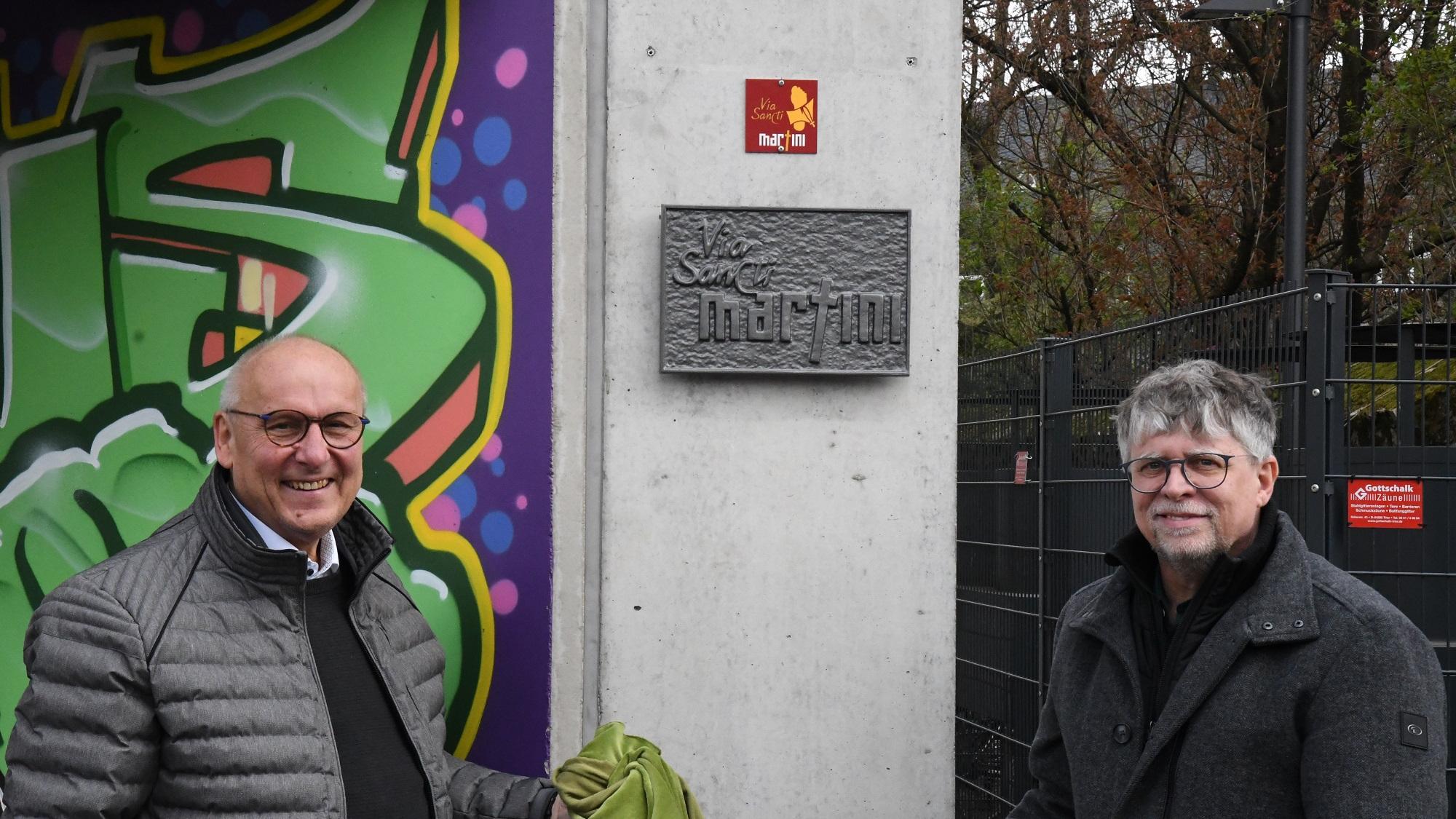 Horst Drach (links) und Andreas Wagner präsentieren die frisch enthüllte Wegmarke und die Plakette zum Martinusweg.