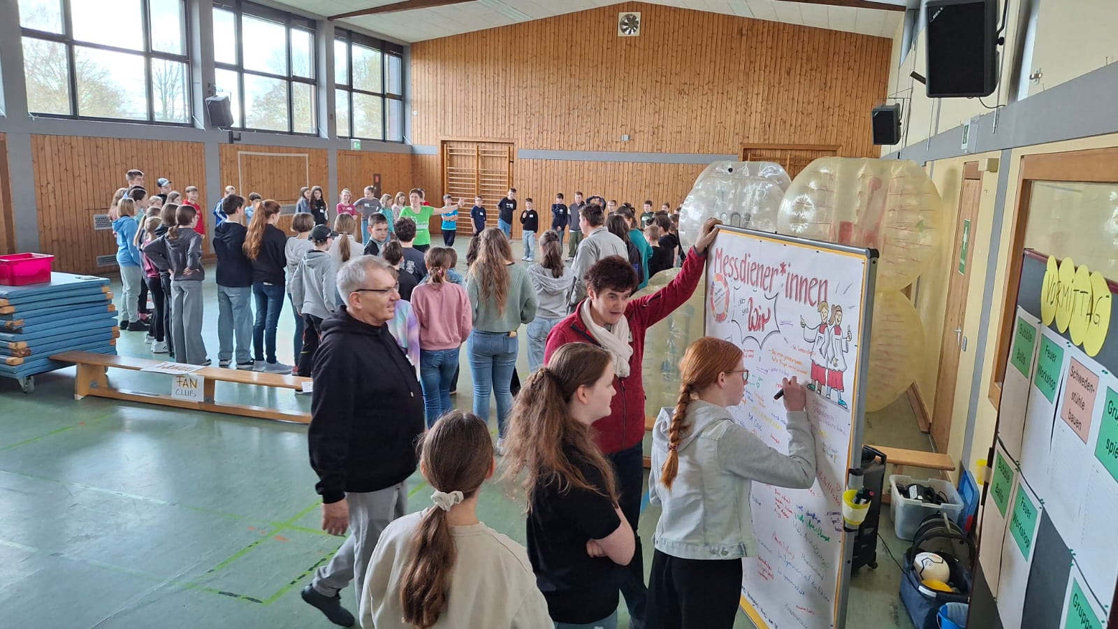 Man sieht Kinder und Jugendliche in einem großen Raum, die in verschiendenen Workshops eingeteilt sind.